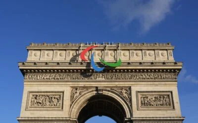 The Arc de Triomphe in Paris with the Paralympic Games logo attached to its top fa&ccedil;ade, set against a blue sky with a few clouds&mdash;an iconic sight reminiscent of kit designer creativity and personalised football kits.