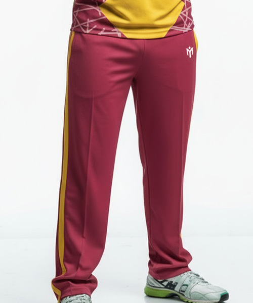 A person wearing maroon athletic track trousers with yellow side stripes, paired with white and green trainers. These bespoke sportswear trousers feature a small white logo on the left thigh. Only the lower half of the body is visible.