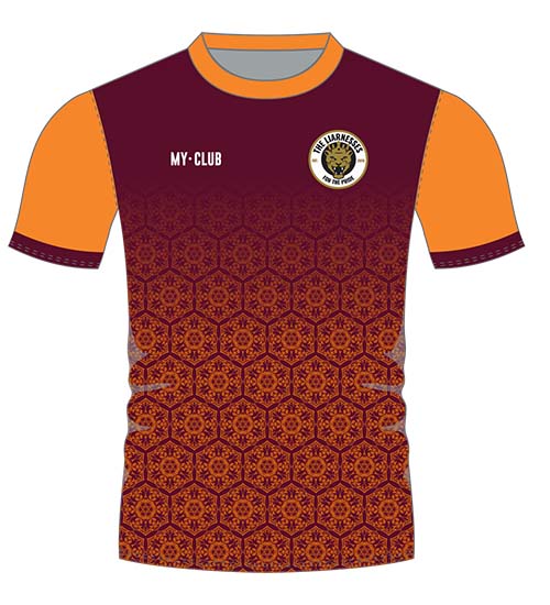 Football shirt with maroon body, intricate geometric patterns, orange sleeves, and collar. A circular team logo and “MY·CLUB” text appear on the chest. The side panels are grey.