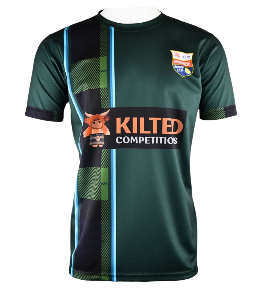 A dark green football shirt with blue and tartan accents, featuring a badge on the left chest, Kilted Competitions logo across the front, and a cartoon mascot holding a Scottish flag.
