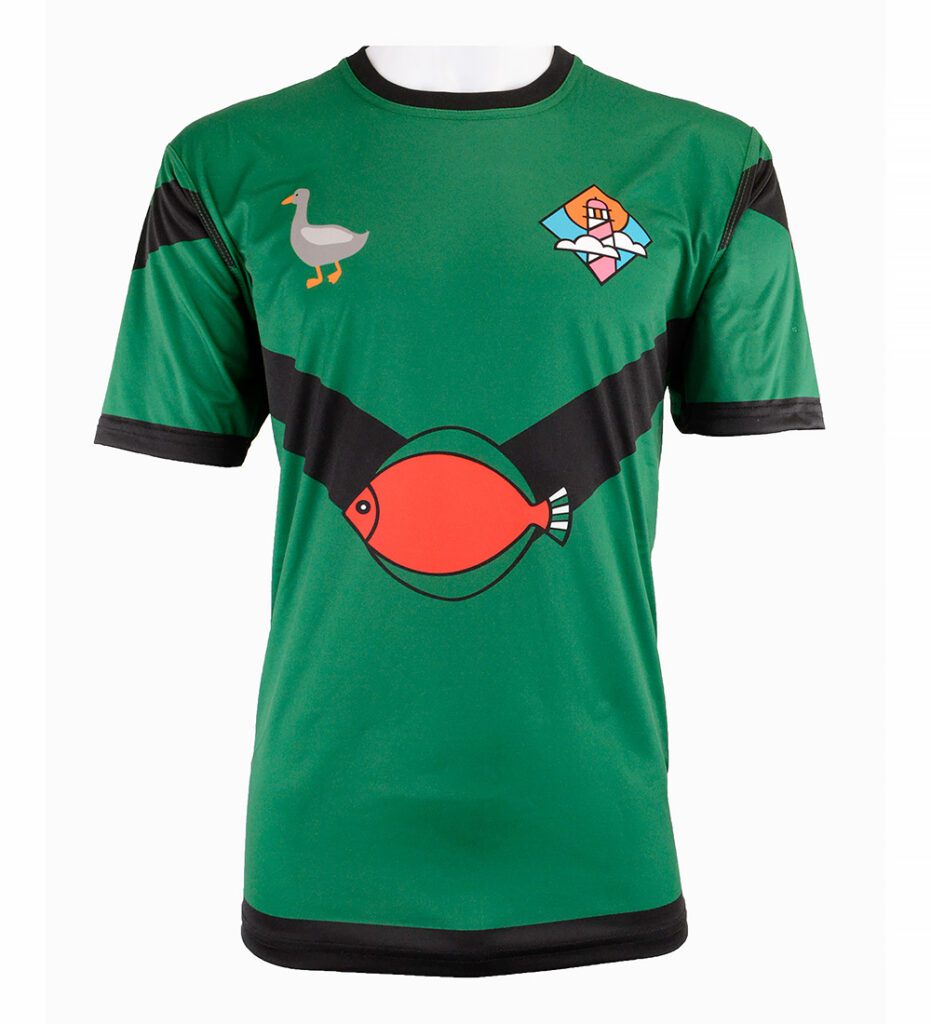 A green football shirt with black accents, featuring a red fish graphic on the chest, a seagull graphic on the right shoulder, and a colourful house and sun logo on the left shoulder.