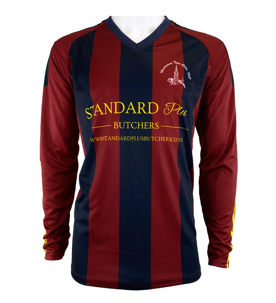 A long-sleeved football shirt with maroon and dark blue vertical stripes, yellow text reading “Standard Plus Butchers,” and a small white logo on the left chest. The shirt has a V-neck and yellow accents on the sleeves.