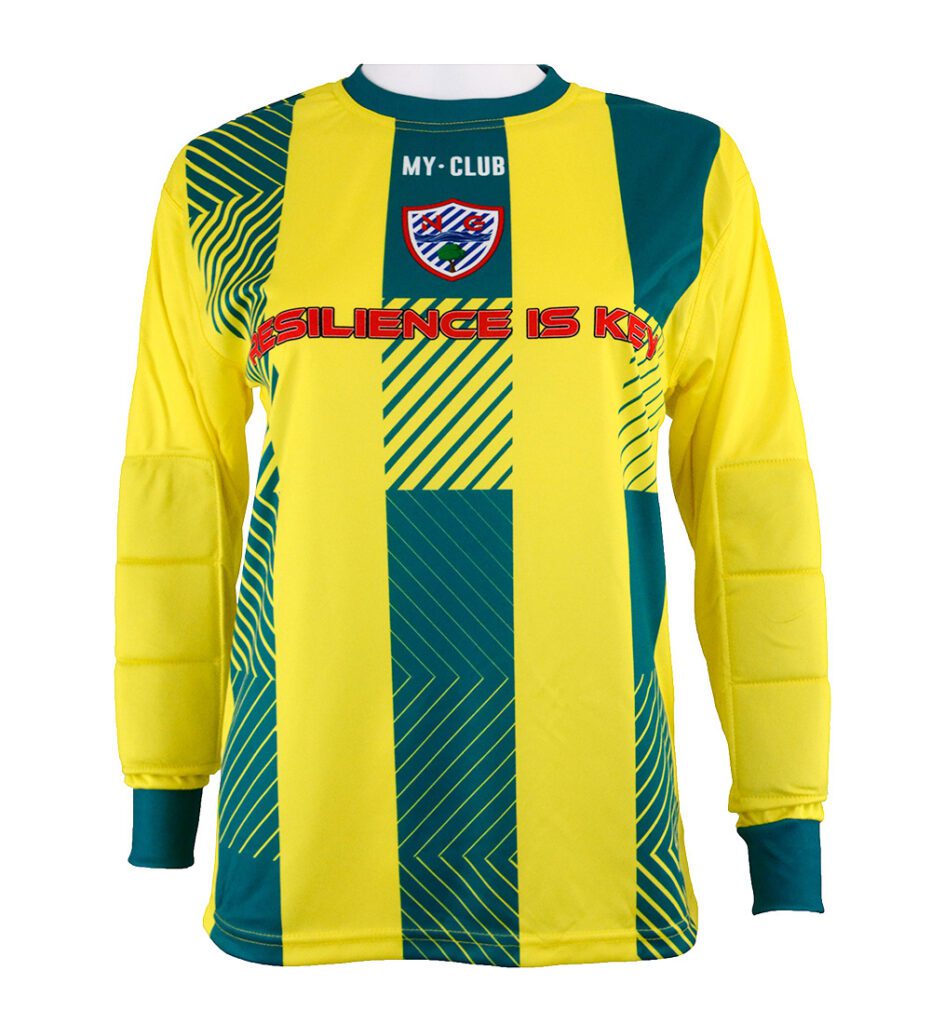 A long-sleeved yellow and green football shirt with geometric patterns, padded elbows, a crest reading MY CLUB, and the text RESILIENCE IS KEY across the chest in bold red letters.