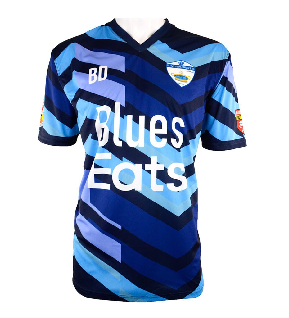 Blue and navy striped football shirt with a chevron pattern, Blues Eats printed on the front, a shield-shaped logo on the chest, initials BD on the right, and sponsor patches on both sleeves.
