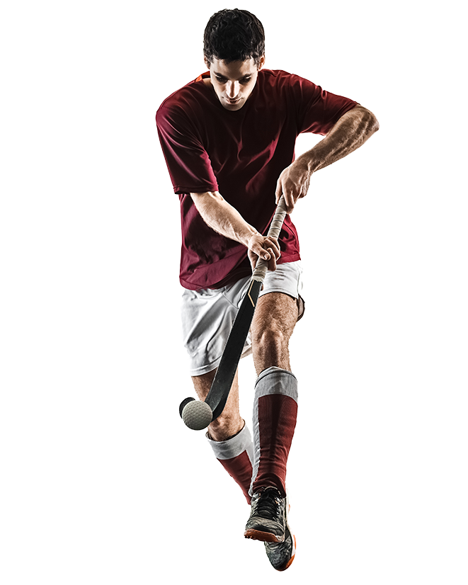 A male field hockey player in a maroon shirt and white shorts is swinging his stick to hit a ball, captured in mid-action against a white background.