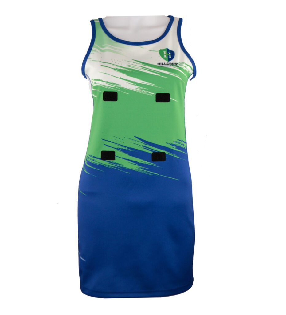 Sleeveless sports dress in green, blue, and white with abstract streak design, Hillcrest logo on the chest, and four black rectangular patches on the front.