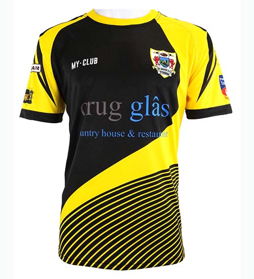 A black and yellow short-sleeved sports jersey with sponsor logos, including “Crug Glas” in blue text on the front, and a crest featuring a dragon and shield on the left chest.