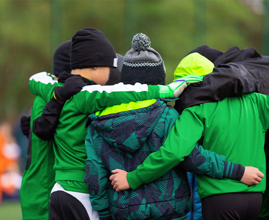 Un groupe de personnes portant des vestes vertes se blottit en plein air, certaines portant des bonnets et des gants.