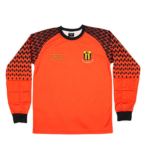 A long-sleeve orange football goalkeeper shirt with black diamond patterns on the shoulders and arms, black cuffs, and a yellow and black crest on the left chest. Text is printed on the right chest.