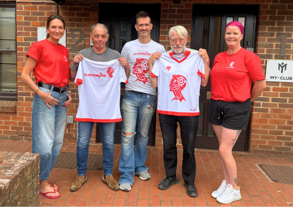 My Club Group team presenting Clockwork charity trustees with their new white and red sublimated Clockwork shirts outside the Oxted office