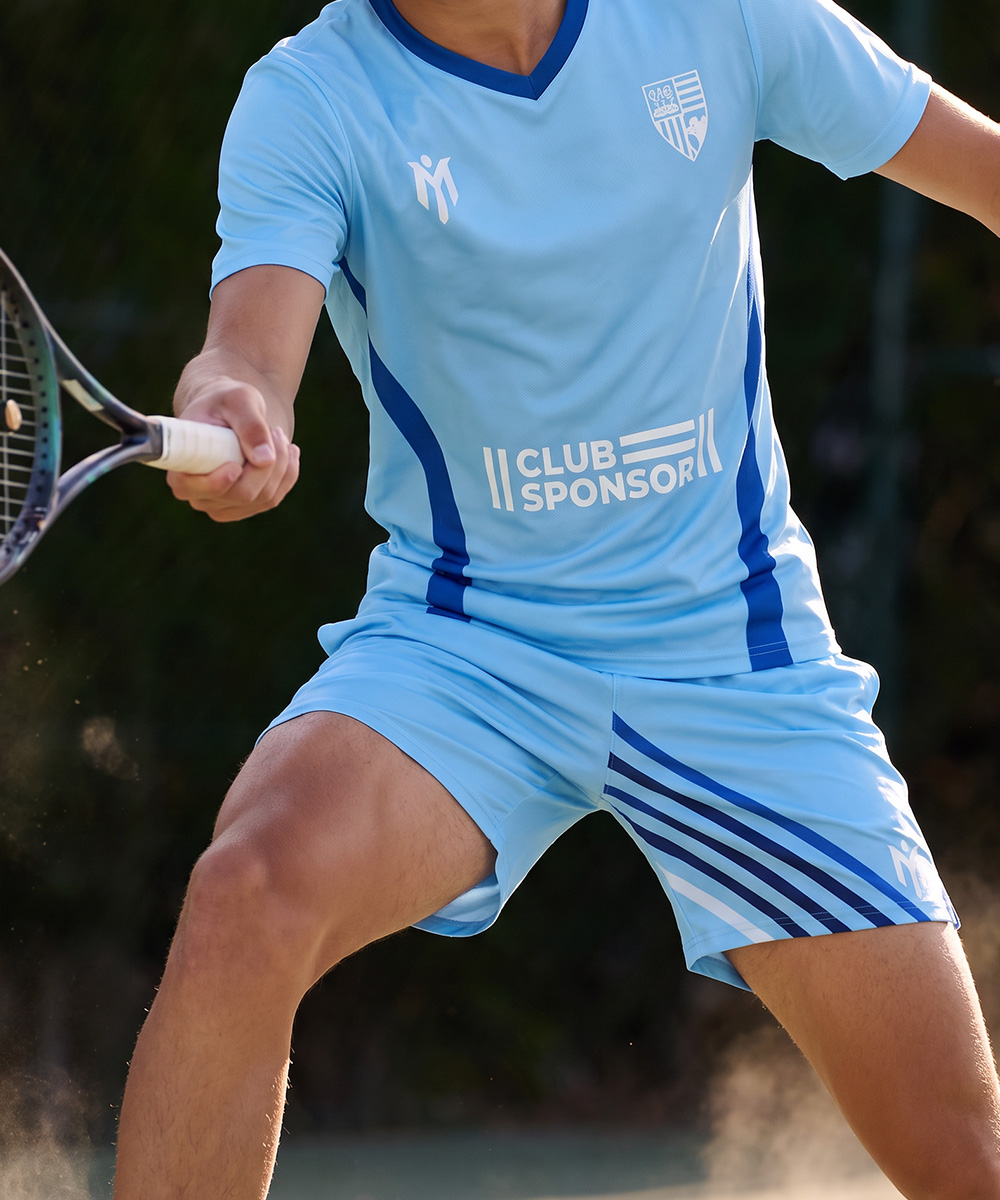 Ein Tennisspieler, der ein hellblaues, farblich abgestimmtes Trikot und maßgeschneiderte Tennishosen trägt, schwingt einen Schläger.