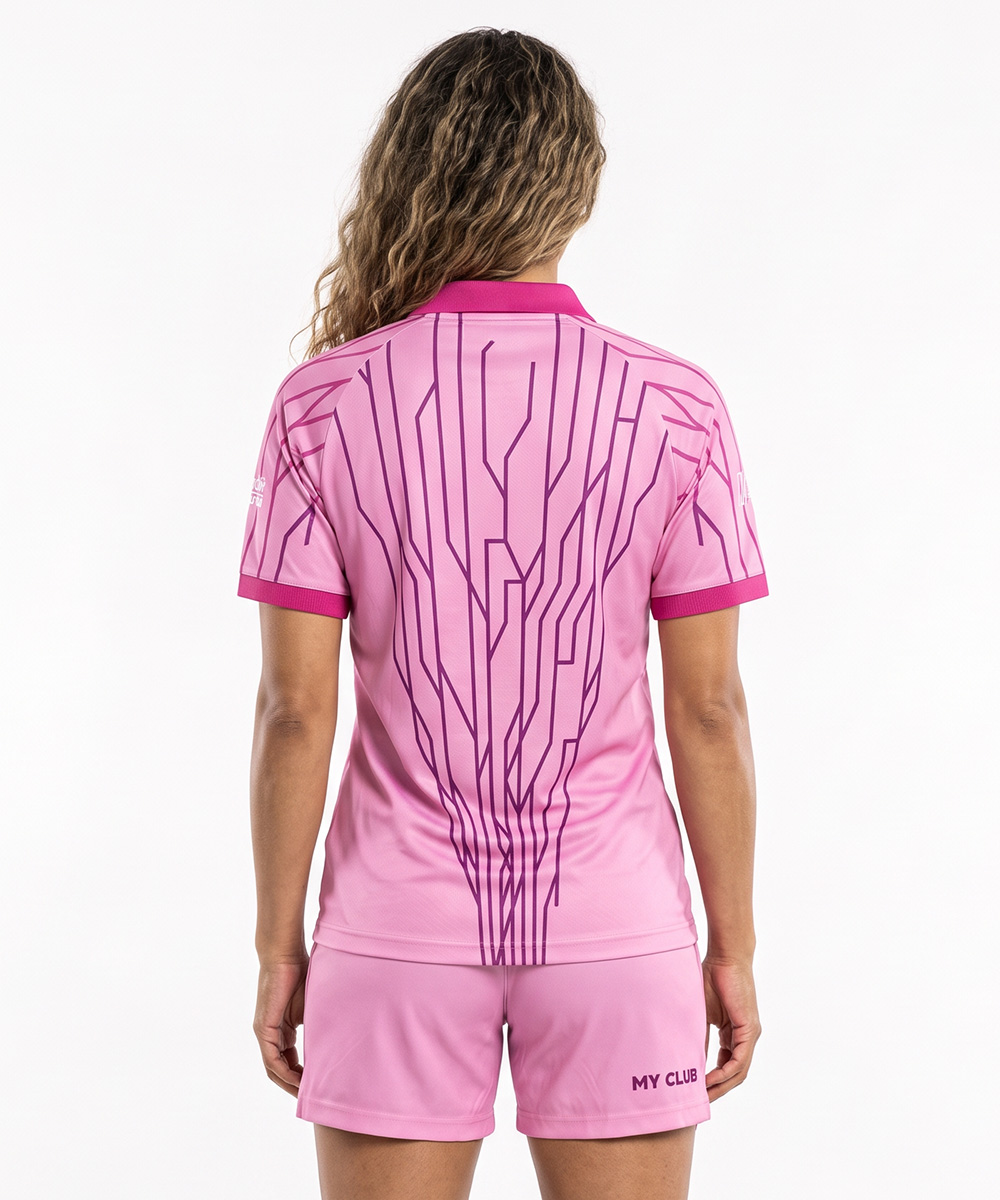 Une personne vue de dos, vêtue d'un polo de tennis haut de gamme rose orné d'un motif de circuit imprimé violet foncé dans le dos, et d'un short rose assorti portant l'inscription « MY CLUB ».