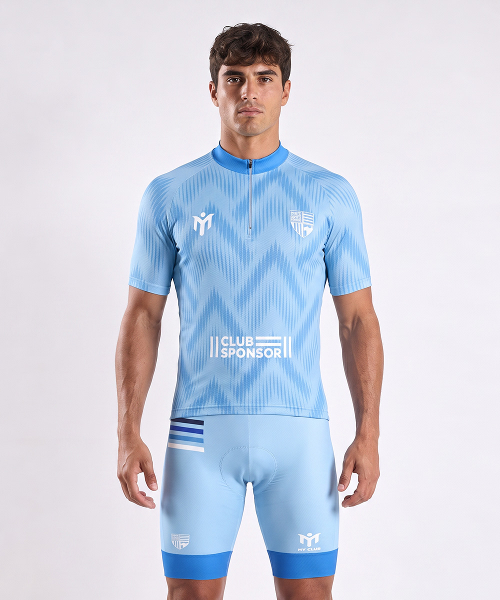 Ein Mann, der ein hellblaues Radtrikot mit Wellenmuster, einen Pullover mit Viertelreißverschluss und dazu passende Radhosen mit Markenlogos trägt.