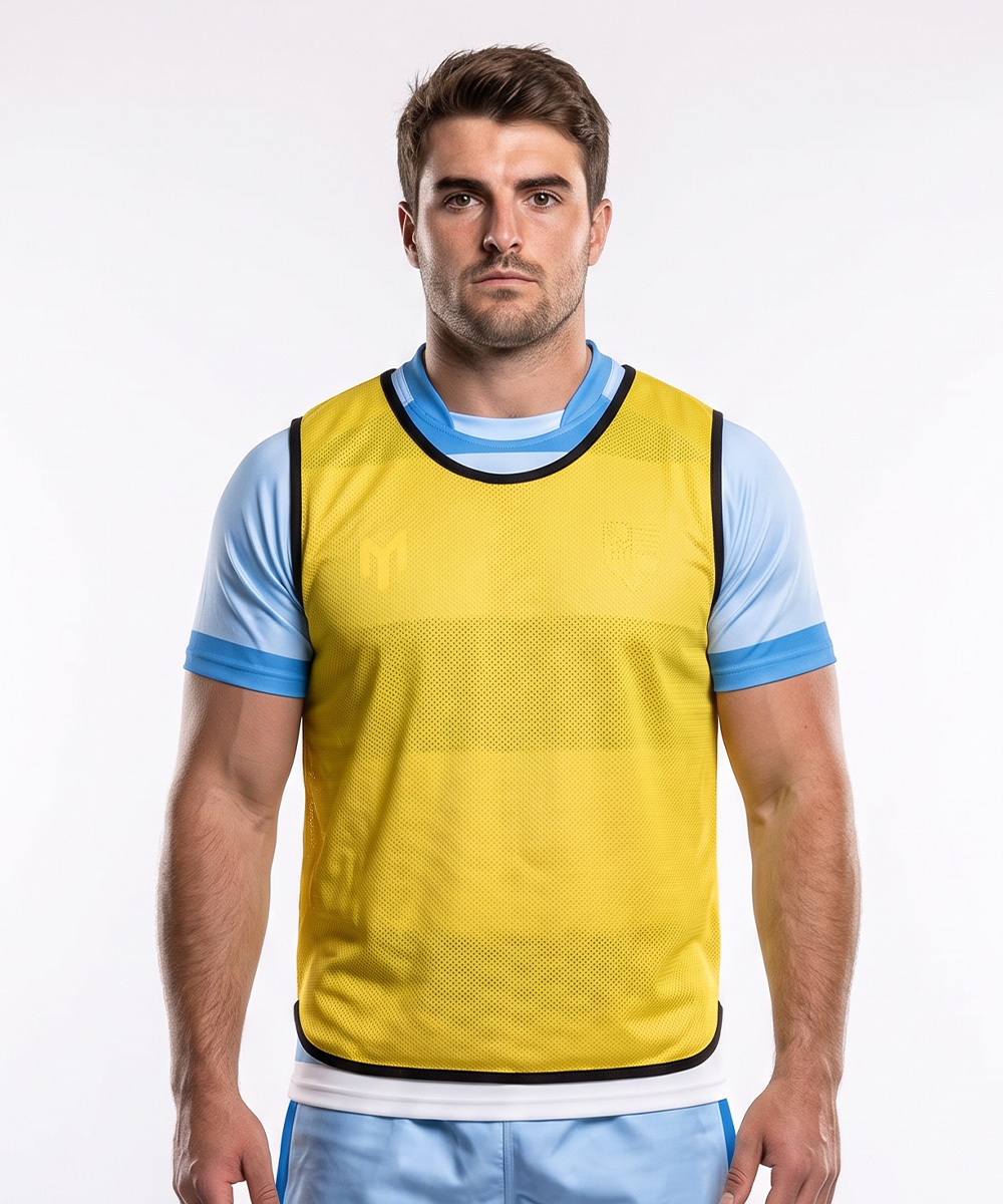 Ein Mann, der ein hellblaues Sportshirt unter einer gelben, maßgeschneiderten Trainingsweste aus Netzstoff trägt.