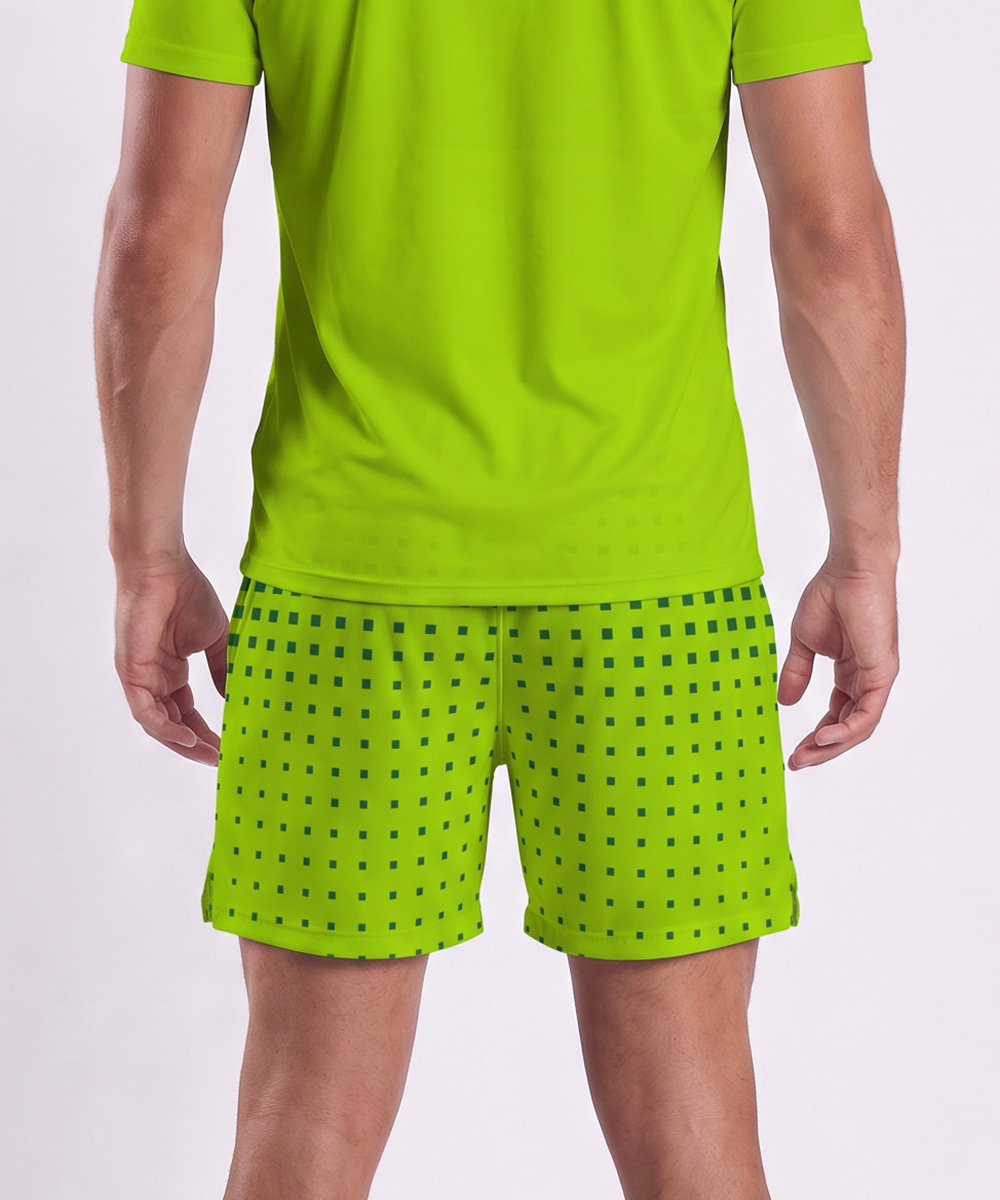 Vue de dos d'une personne portant une chemise à manches courtes vert vif et un short de tennis sur mesure en tissu recyclé, de couleur vert citron, orné d'un petit motif carré foncé.