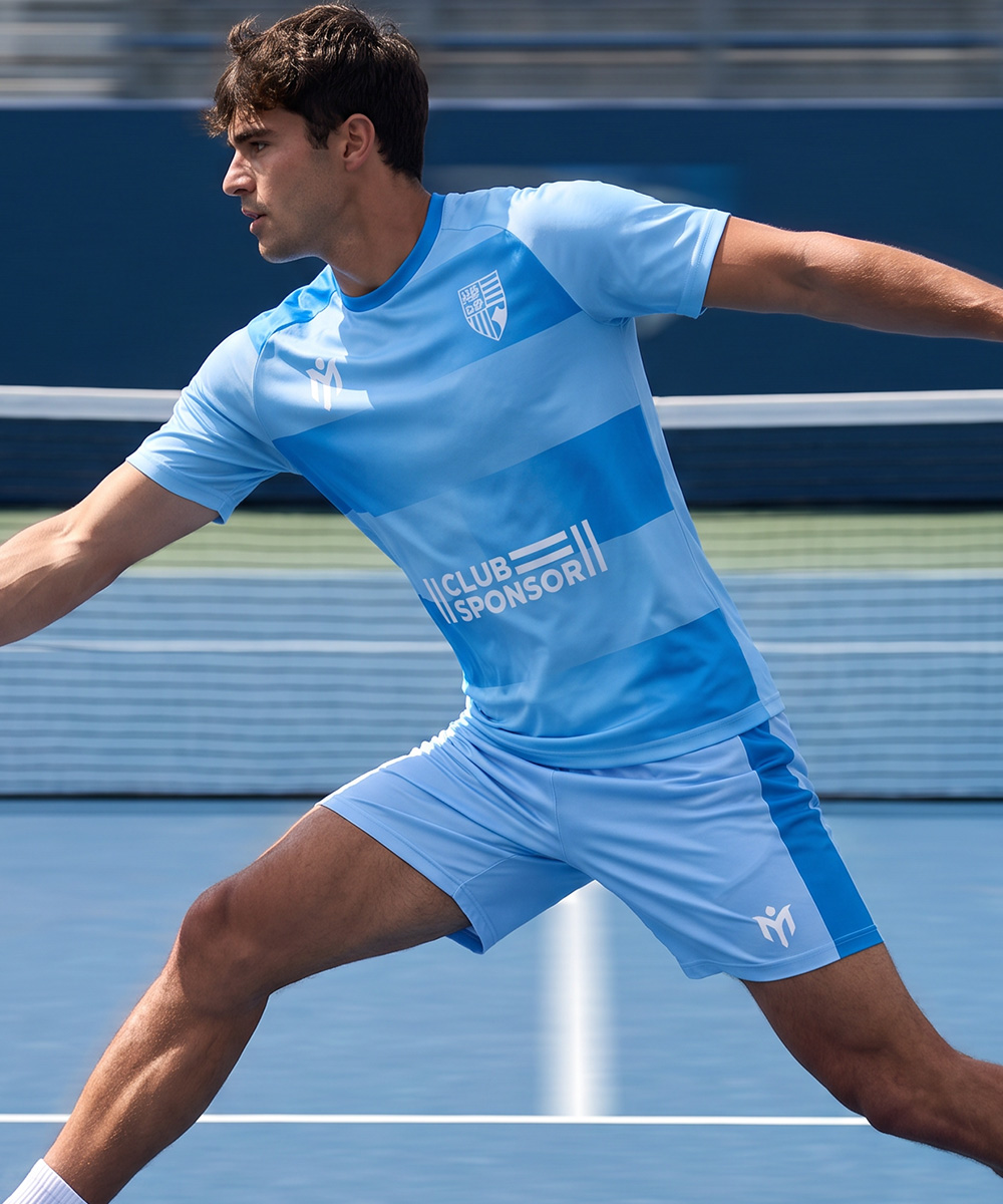 Un joueur de tennis, vêtu d'un t-shirt de tennis personnalisé et d'un short assorti, effectue une fente sur un court bleu.
